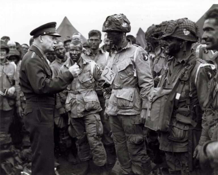 Gen. Dwight D. Eisenhower gives the order of the Day. "Full victory -- nothing else" to paratroopers in England just before they board their airplanes to participate in the first assault in the invasion of the continent of Europe. The Soldier wearing No. 23 is Wallace Strobel, who began his military career with the Michigan National Guard